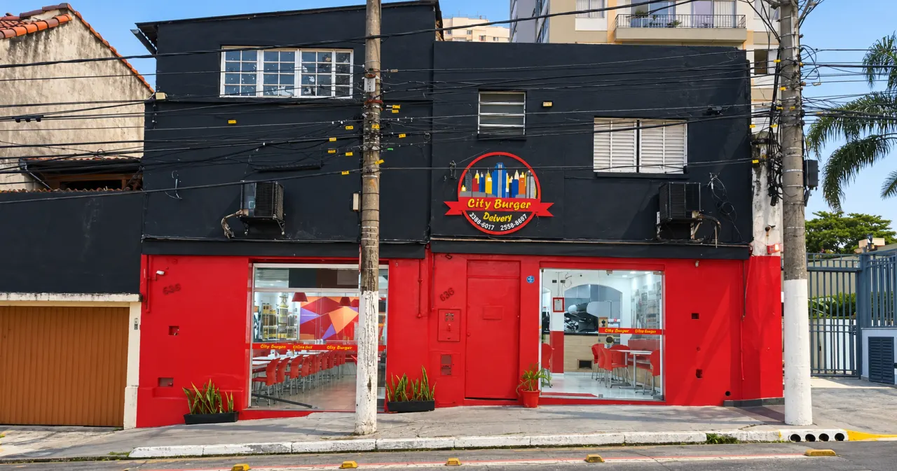 Fachada do City Burger: prédio de dois andares com térreo vermelho, andar superior preto e o logotipo do restaurante acima da entrada
