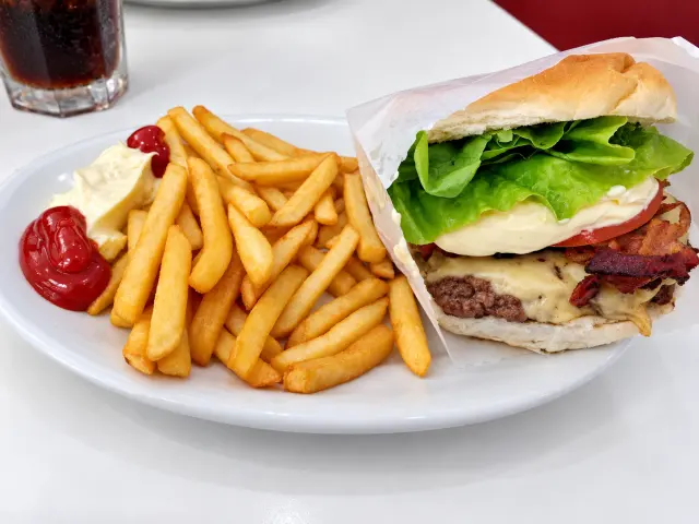 Hambúrguer com bacon e queijo acompanhado de batatas fritas, ketchup e maionese