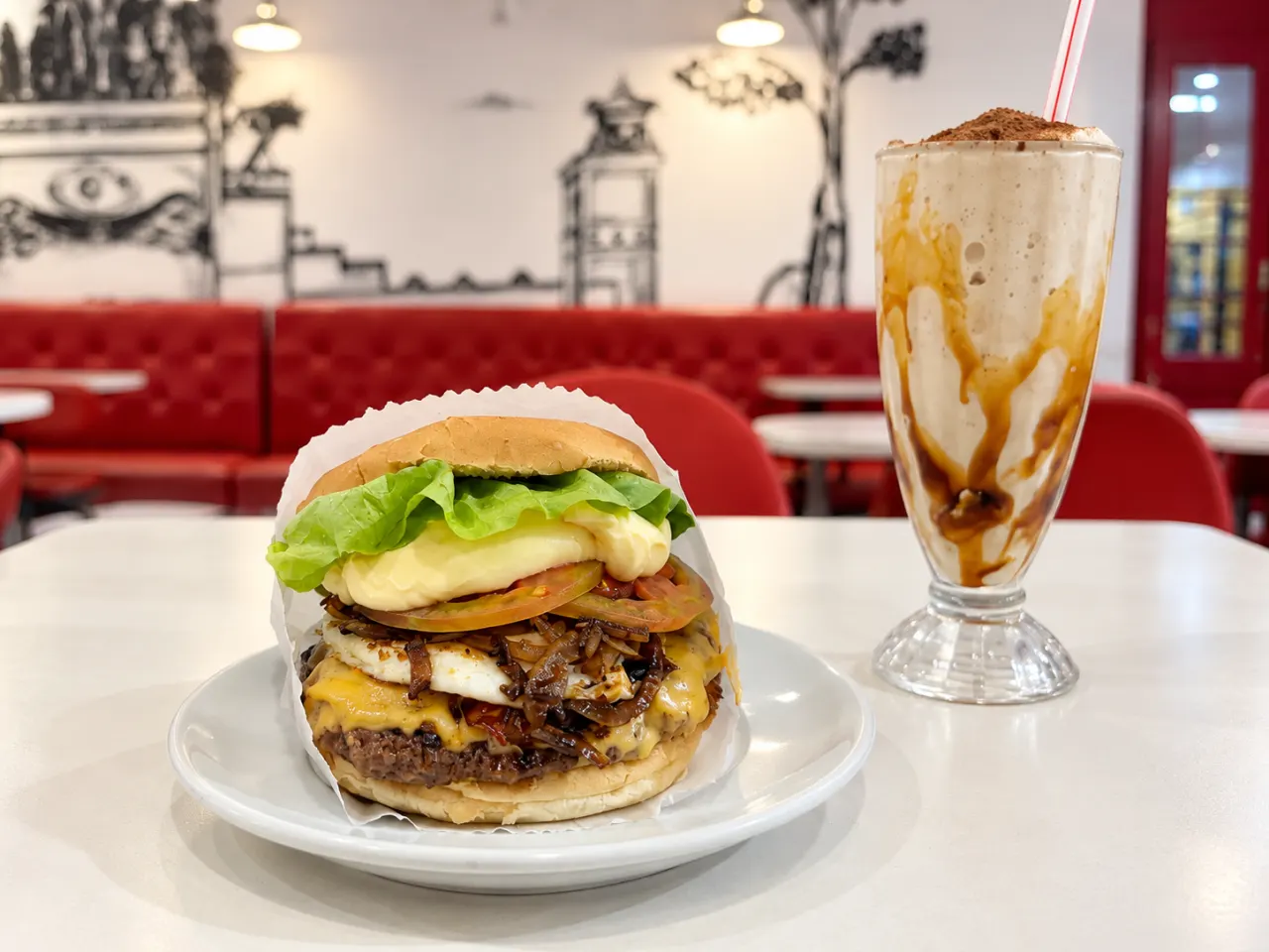 Hambúrguer e milk-shake servidos em uma mesa do salão do City Burger